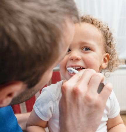 father brushing teeth to son