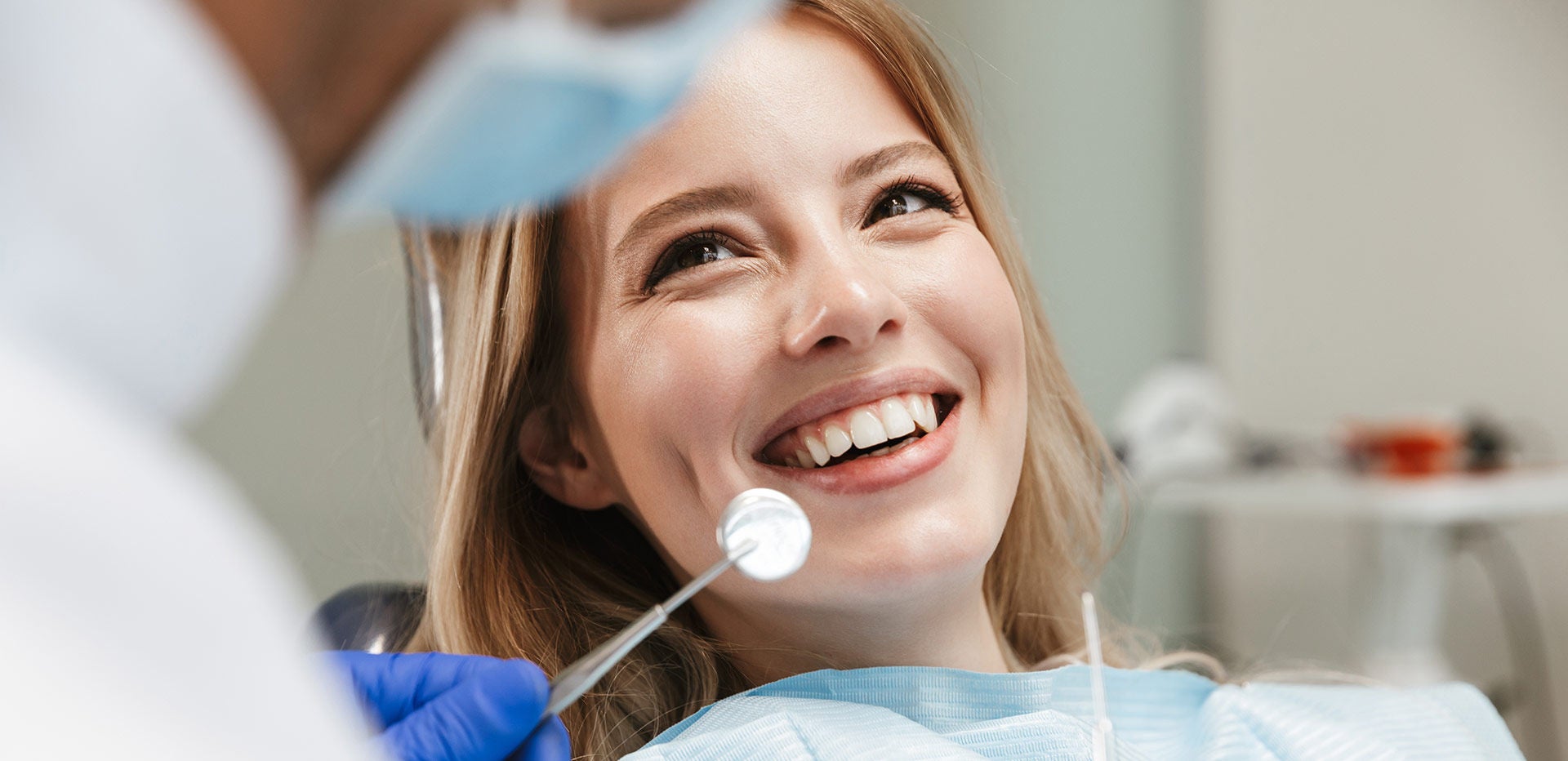 Image of pretty woman sitting in dental chair while professional doctor fixing her teeth